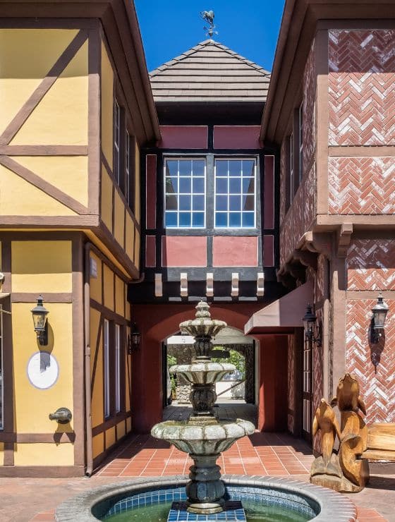 An outdoor shopping area with decorative, Bavarian style buildings and a fountain